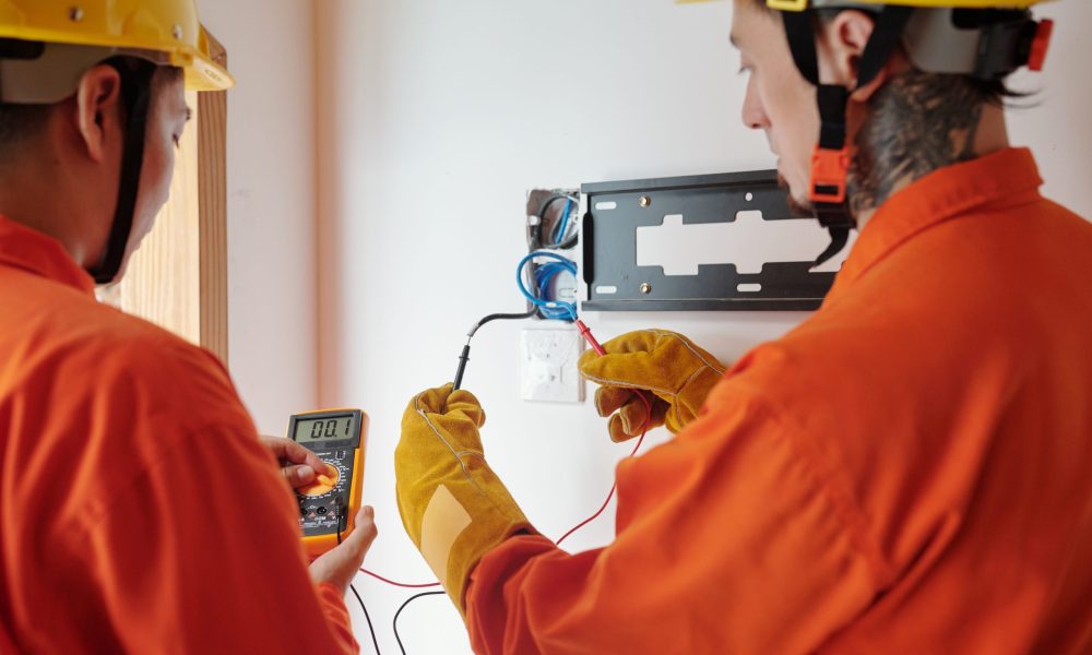 Electricians wearing protective gloves when testing electrical wires for amperage