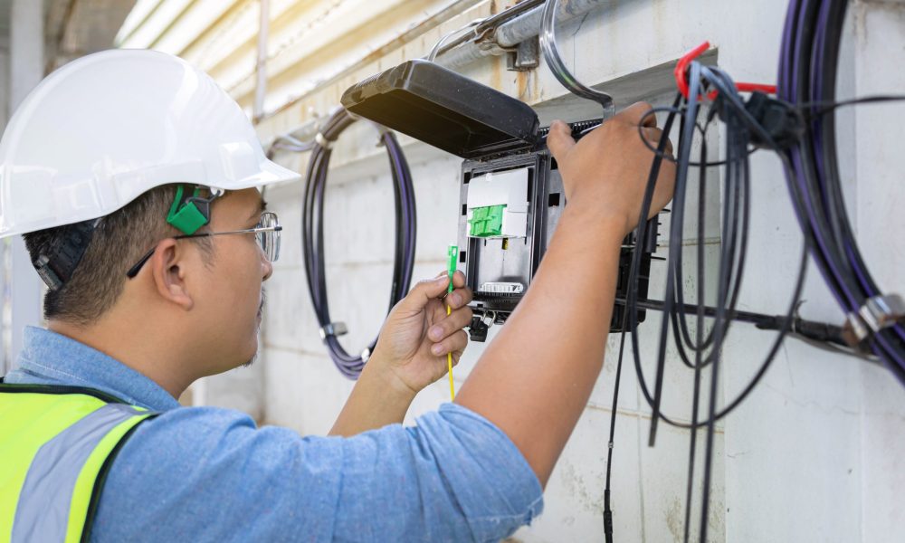 Engineer or technician checking fiber optic cables in internet splitter box.Fiber to the home equipment. FTTH internet fiber optics cables and cabinet.