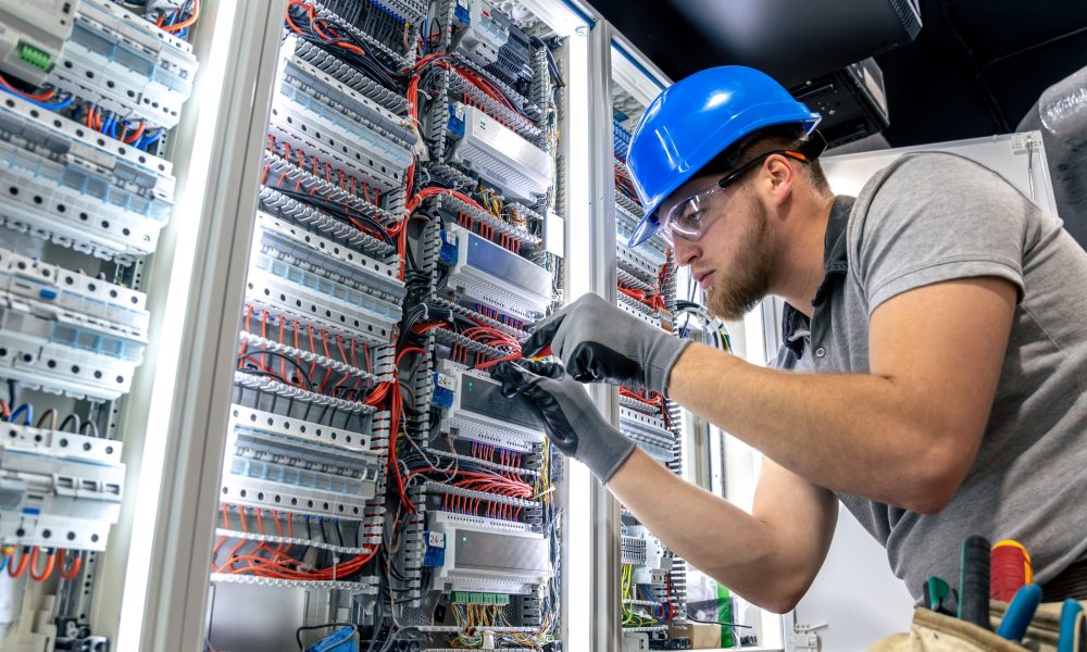 Male electrician in uniform working in a switchboard. Electricity. High quality photo. Male electrician in hard hat. A male electrician solves a problem with electricity. SSUCv3H4sIAAAAAAAAA41PQY6DMAz8i88gBVJg4StVDyFxqVVKqsRstUL5+zqUaq+b04wnnhlvQA4GaE3T9QpVWZ9UV1bVVZWjrevypHvdNLpHc3VQgDOMMFRa90p/Kd22Xd0reQWMJpKFYQOa5zVyMEx+gUGUgIvDsEN0xD6QmYWlAiIbXiNGWRNmxXsSdecfv/OW51JQwuM6ZpCKf84uBZgJF/uT/VMuMqPZ484i3V+M4XFke77lihk+A1lapqOTnOIfb7x4zrt7Ant7J3csv8+4kUxDzoL1OXvj0B3yOj6I+UMDfhO+/n6nlH4B3lC4PIQBAAA=